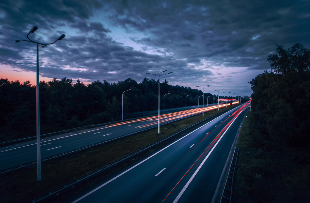 Long exposure of a highway in Hasselt, Belgium, capturing light trails under a cloudy evening sky.